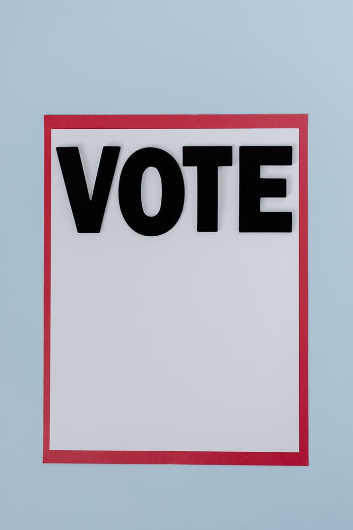 A bold Vote sign with a red border on a pale blue background.